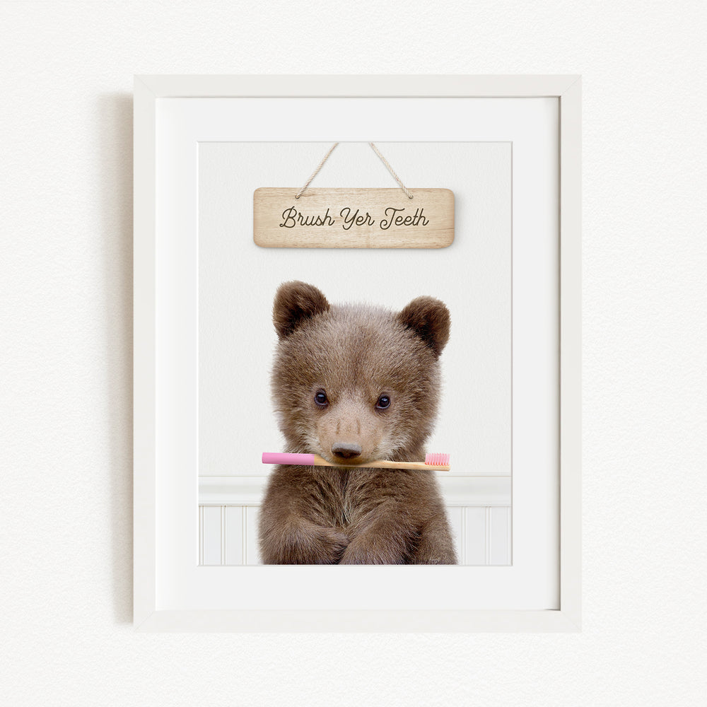 A cute brown bear holding a pink toothbrush in front of a wooden sign that says "Brush Your Teeth".