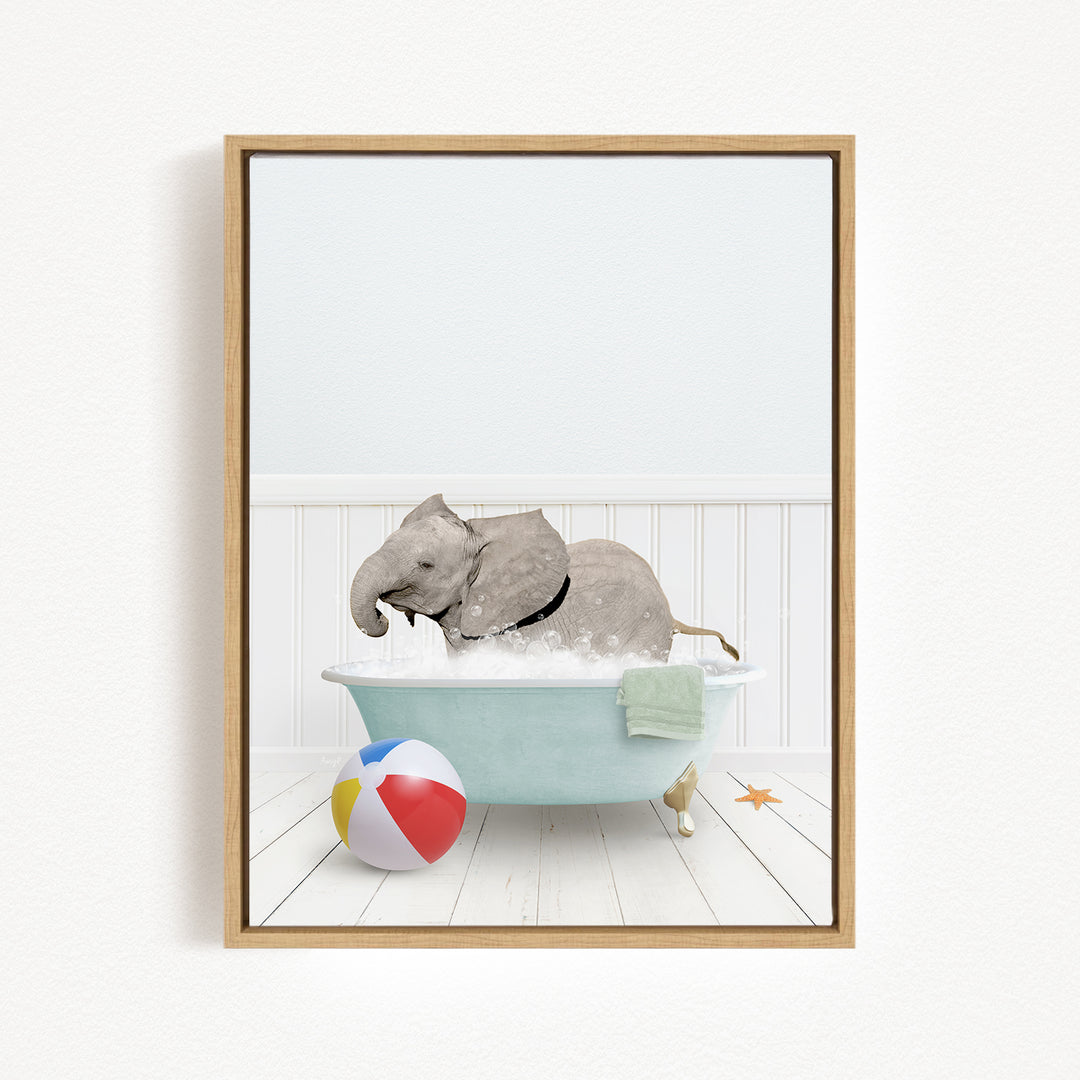 A gray elephant is sitting in a blue bathtub filled with water, surrounded by a beach ball and a towel.