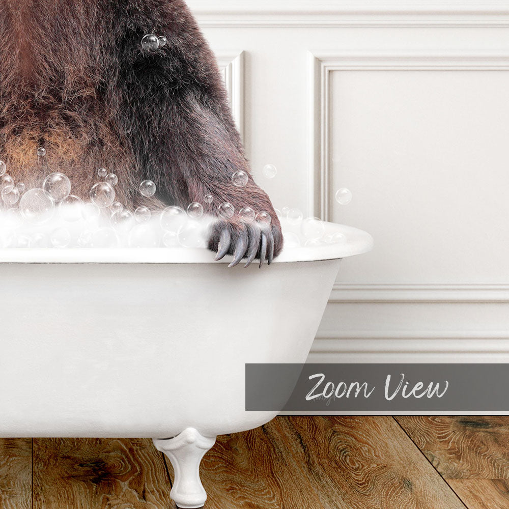 A close-up image of a bear's paw resting on the edge of a white bathtub filled with bubbles, with a wooden floor visible in the background.