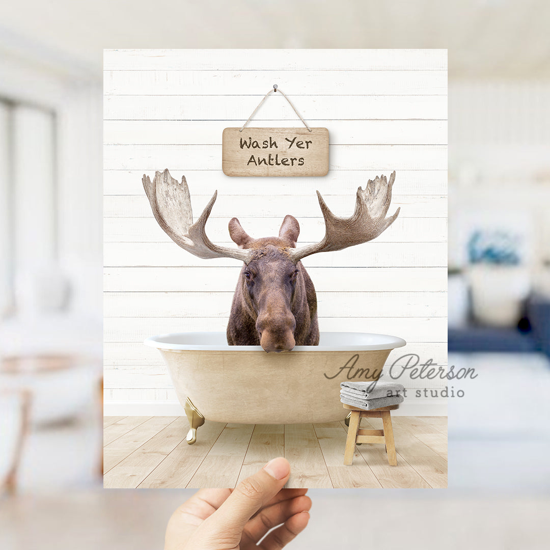 a hand holding up a photo of a moose in a bathtub