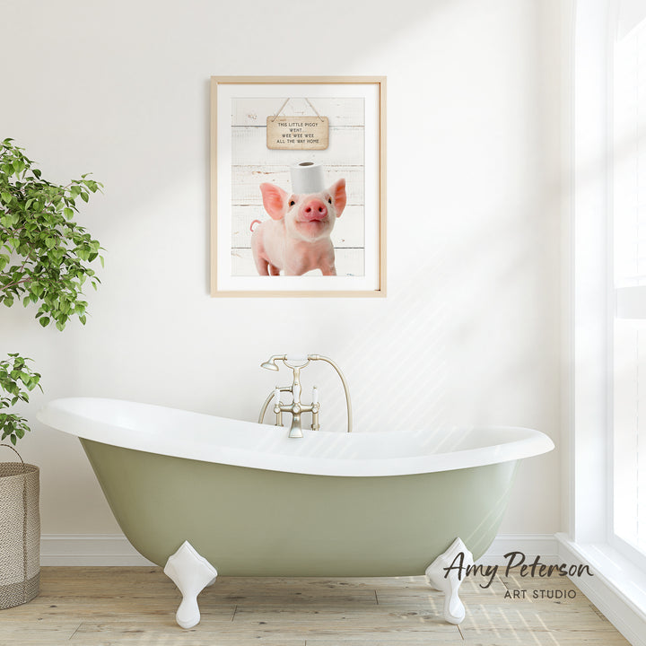 a bathroom with a green clawfoot bathtub, a framed picture of a pig with a toilet paper roll on its head, and a potted plant on the left side of the frame.