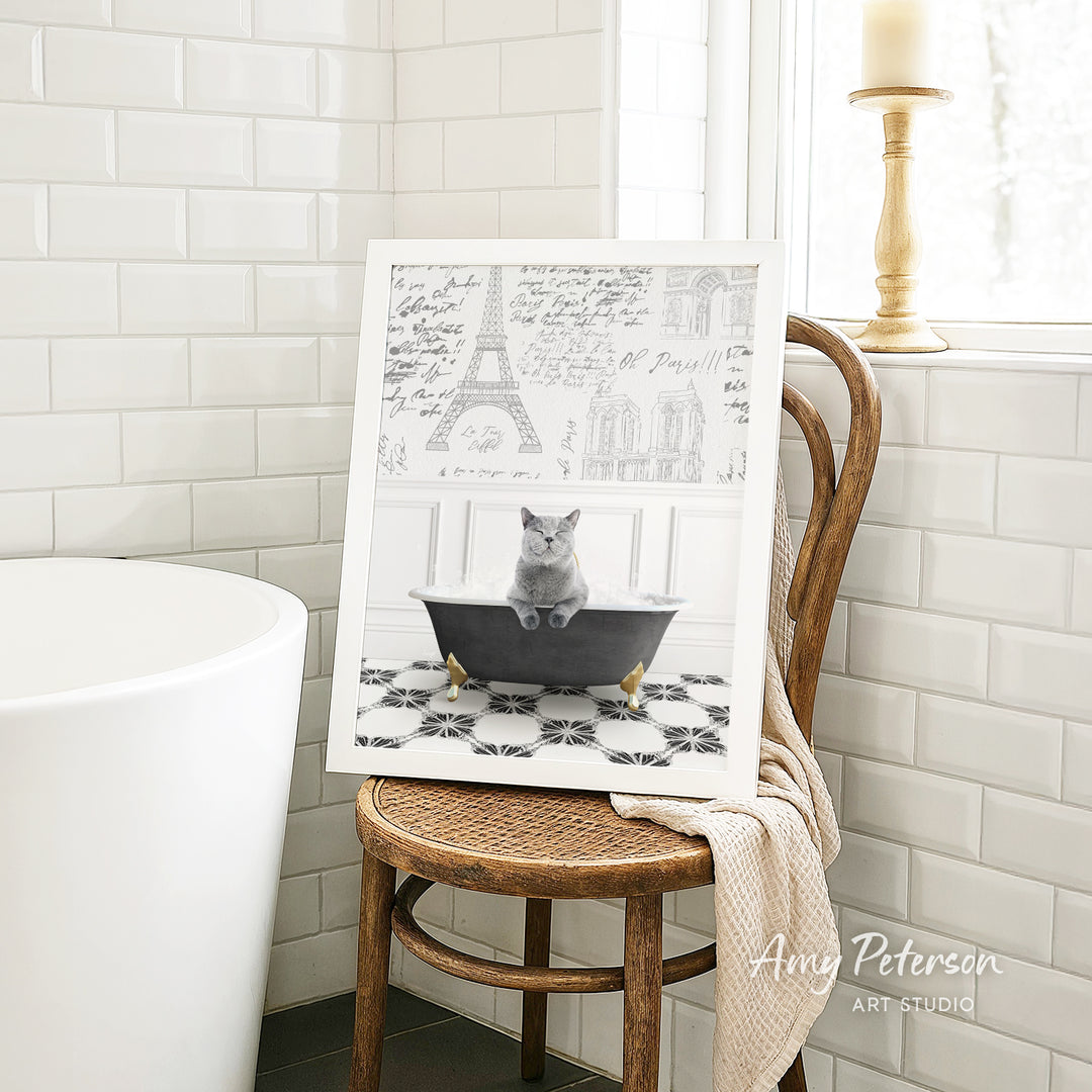 A framed image of a cat sitting in a bathtub, with a drawing of the Eiffel Tower in the background.
