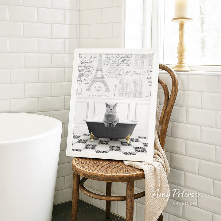 A framed image of a cat sitting in a bathtub, with a drawing of the Eiffel Tower in the background.