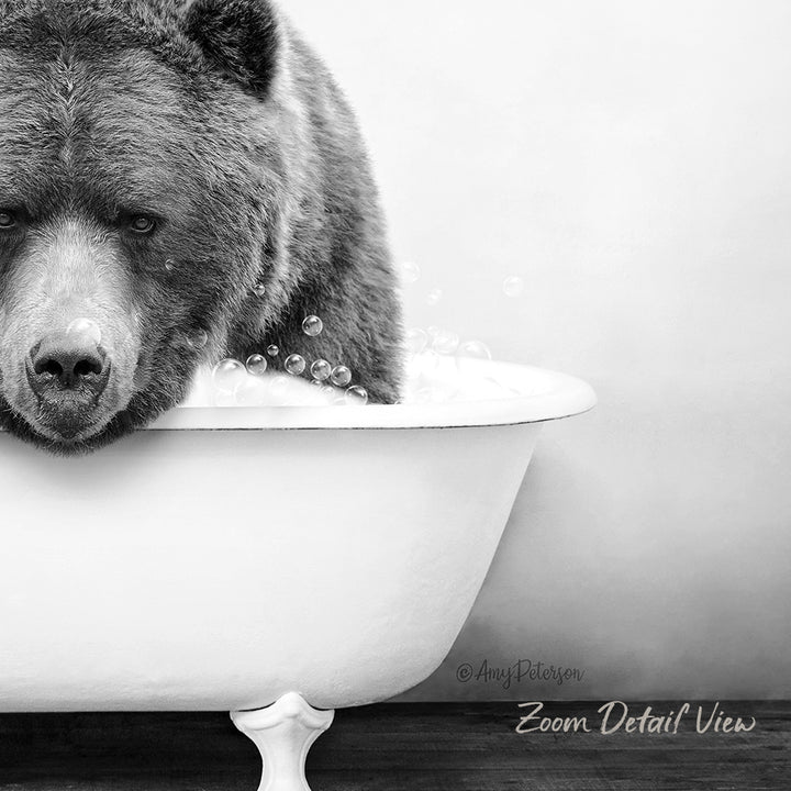 A black and white image of a bear sitting in a bathtub filled with water and bubbles.