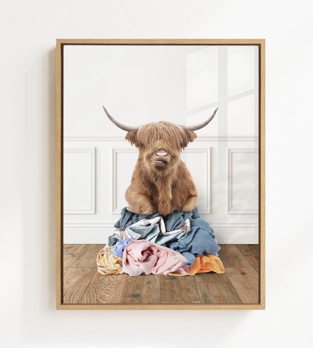 A brown cow with long horns is sitting on a pile of clothes in the center of the image.