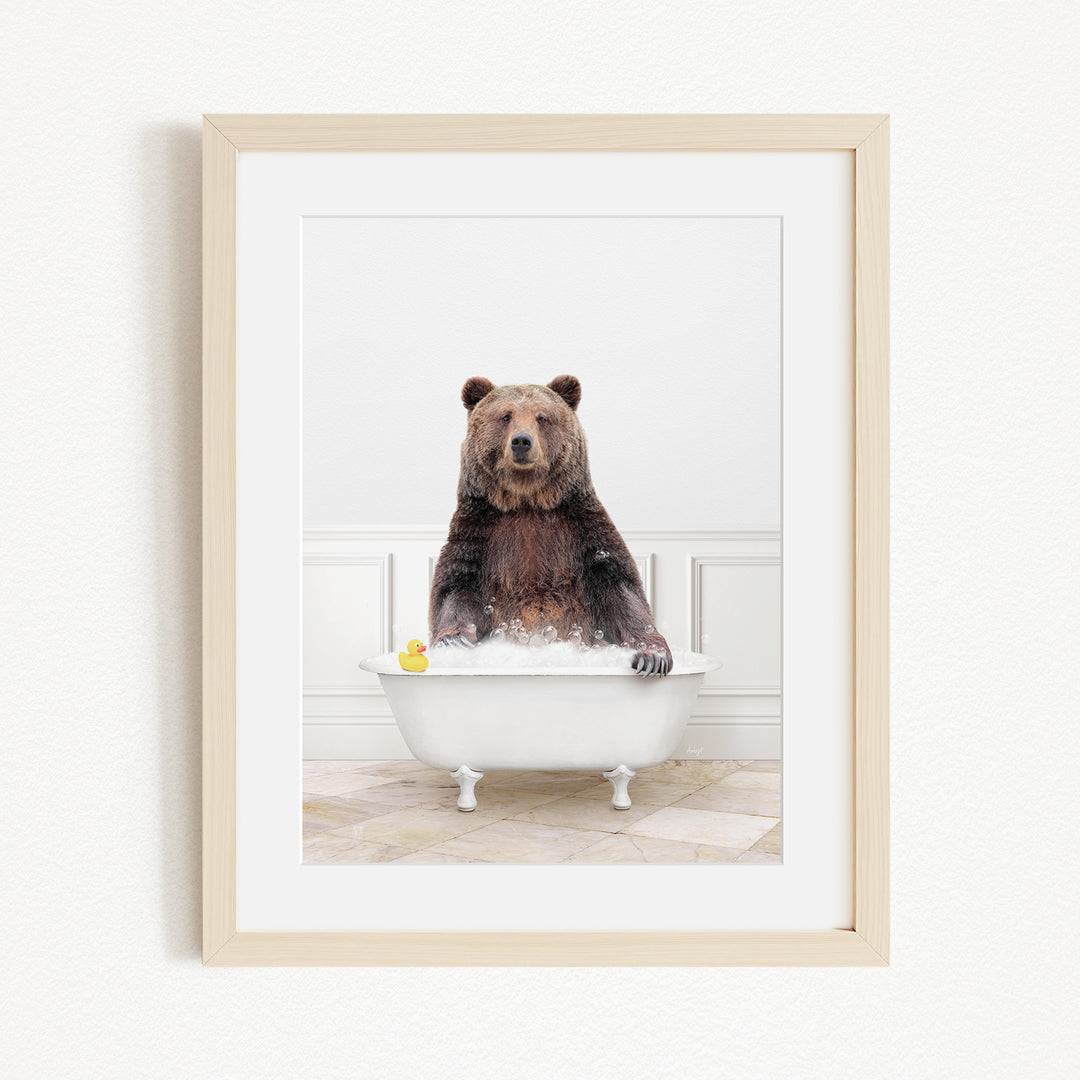 A brown bear sitting in a white bathtub, with a yellow rubber duck floating in the water.