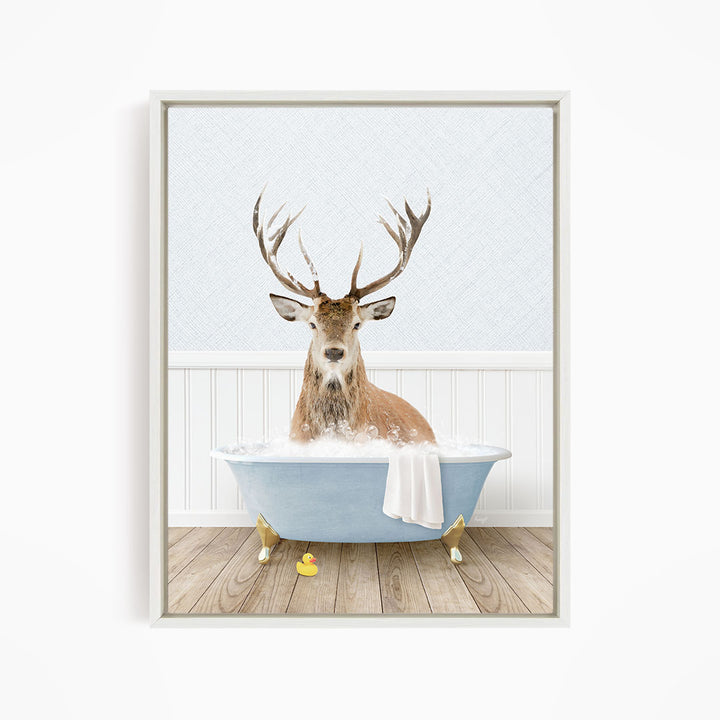 A deer with large antlers is sitting in a blue bathtub filled with water, surrounded by rubber ducks.