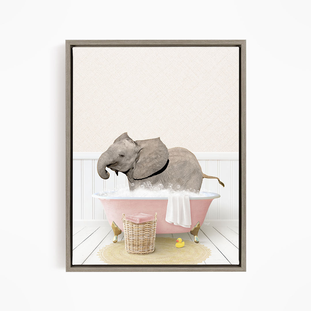 A gray elephant is sitting in a pink bathtub filled with water, surrounded by a yellow rubber duck and a basket.