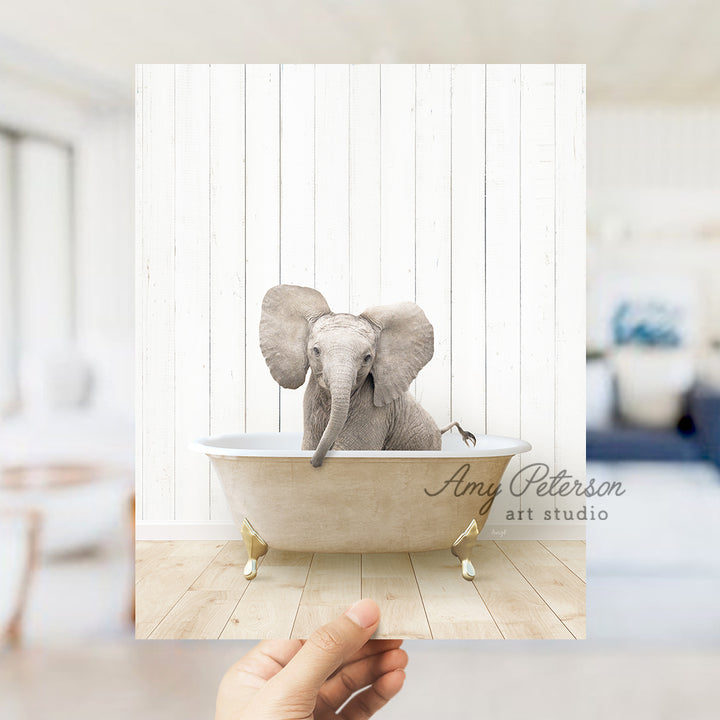 a hand holding a photo of an elephant in a bathtub