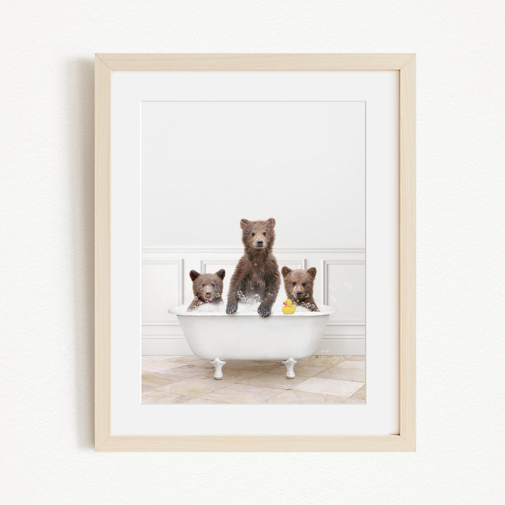 A framed image showing three brown bears sitting in a white bathtub, with one bear holding a yellow rubber duck.