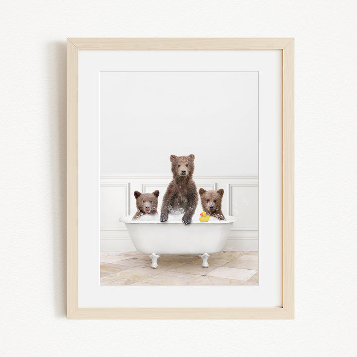 A framed image showing three brown bears sitting in a white bathtub, with one bear holding a yellow rubber duck.