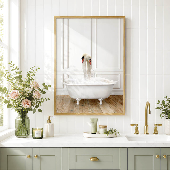 A framed image of two swans sitting in a bathtub is displayed on a white tiled wall above a bathroom vanity with a white countertop.