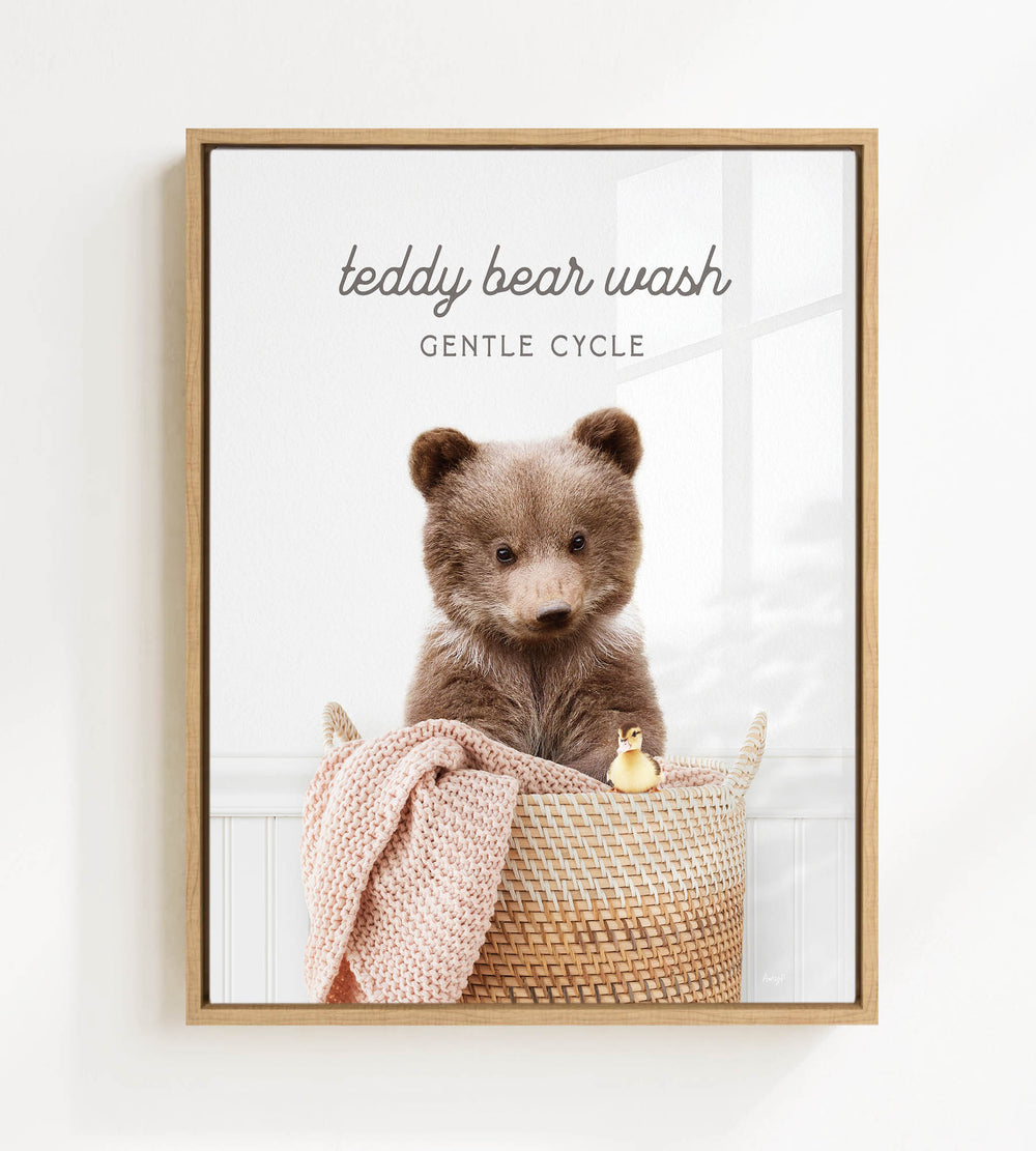 A teddy bear sitting in a woven basket, with a blanket and a toy duck nearby.