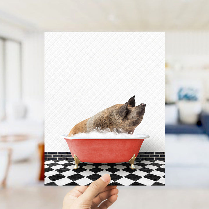 A hand holds up a framed image of a pig sitting in a red bathtub filled with bubbles, with a black and white checkered floor in the background.