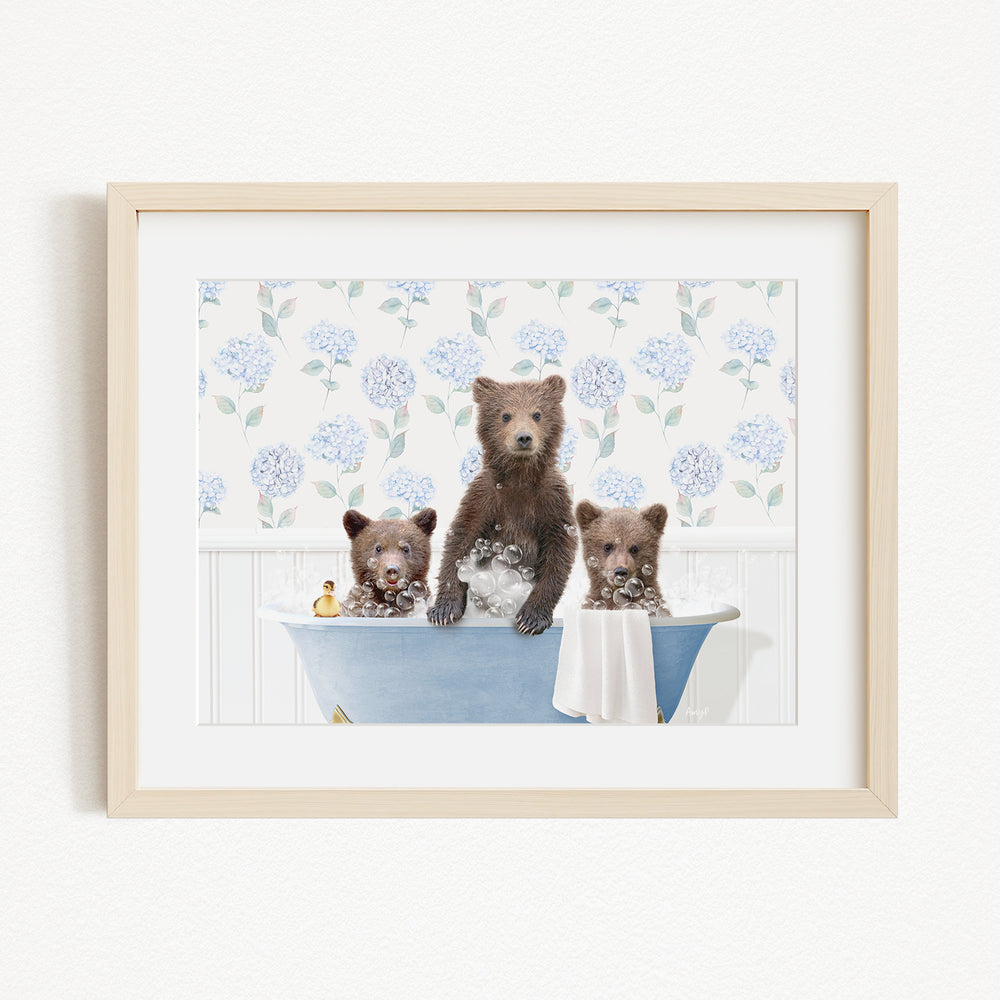 A framed image depicting three bears sitting in a blue bathtub, with one bear standing and the other two sitting.