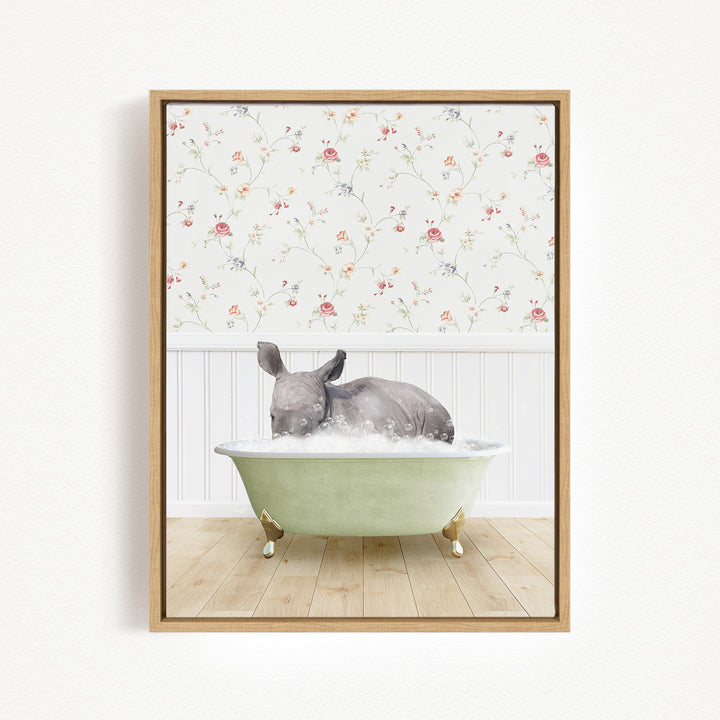 A gray rhinoceros is sitting in a green bathtub filled with water, surrounded by a floral wallpaper.