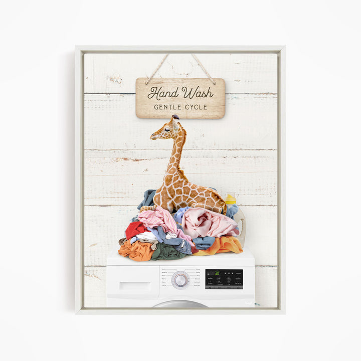 A giraffe sitting on a pile of laundry next to a hand wash sign, with a washing machine below.