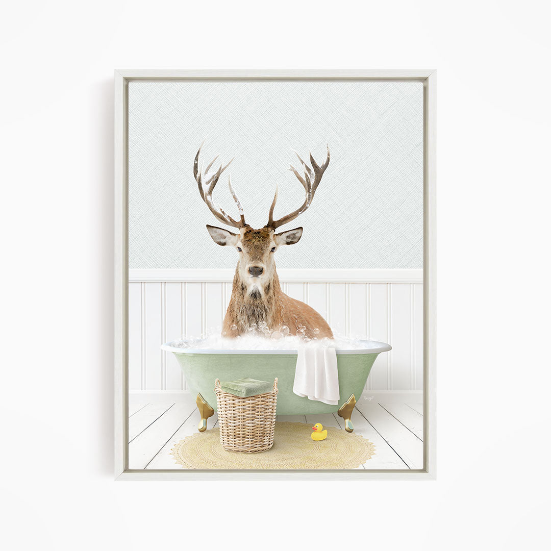 A deer with large antlers is sitting in a green bathtub filled with bubbles, surrounded by a yellow rubber duck and a woven basket.