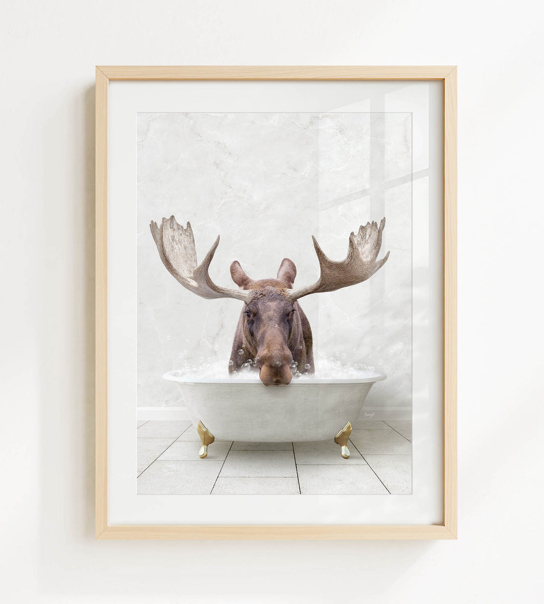 A moose with large antlers is sitting in a white bathtub, surrounded by bubbles, in a framed artwork.
