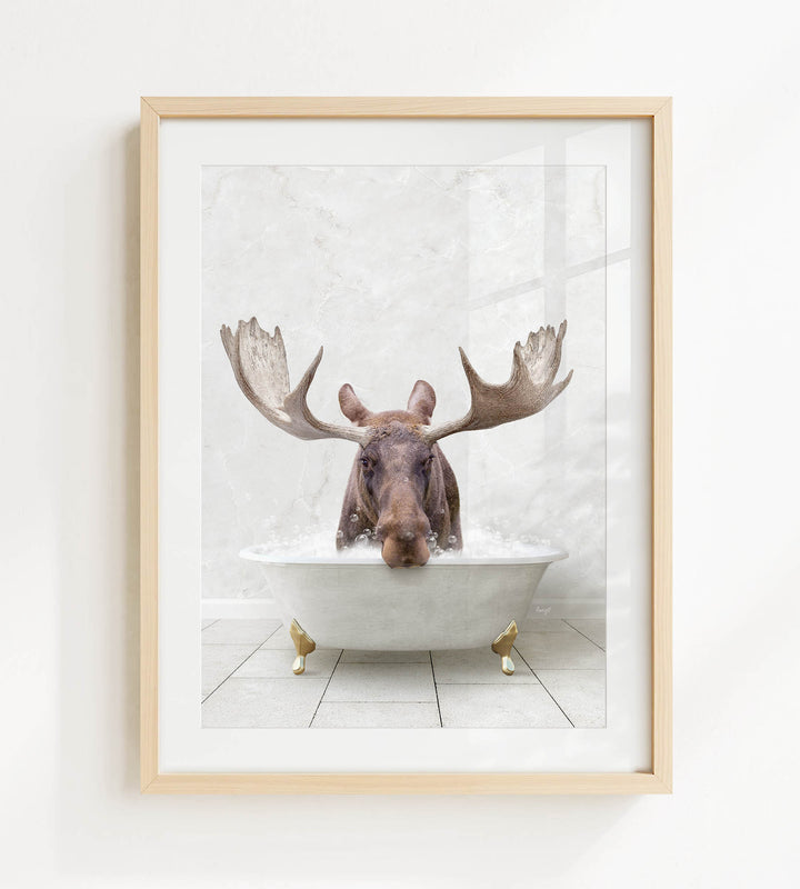 A moose with large antlers is sitting in a white bathtub, surrounded by bubbles, in a framed artwork.