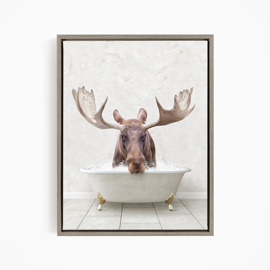 A moose with large antlers is sitting in a white bathtub filled with water, creating a whimsical and humorous scene.