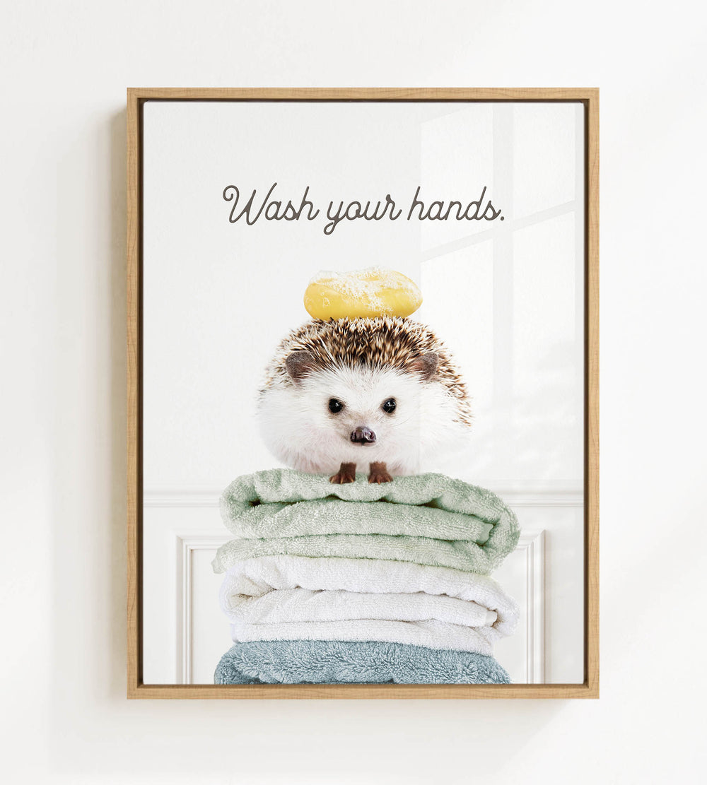 A cute hedgehog sitting on a stack of folded towels, with the text "Wash your hands" written above it.