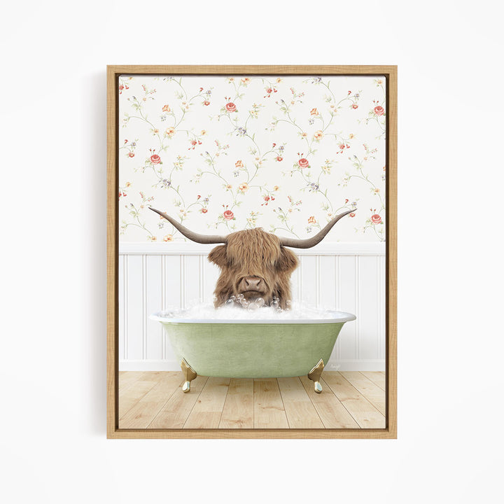 A brown cow with long horns is sitting in a green bathtub filled with water, surrounded by a floral wallpaper.
