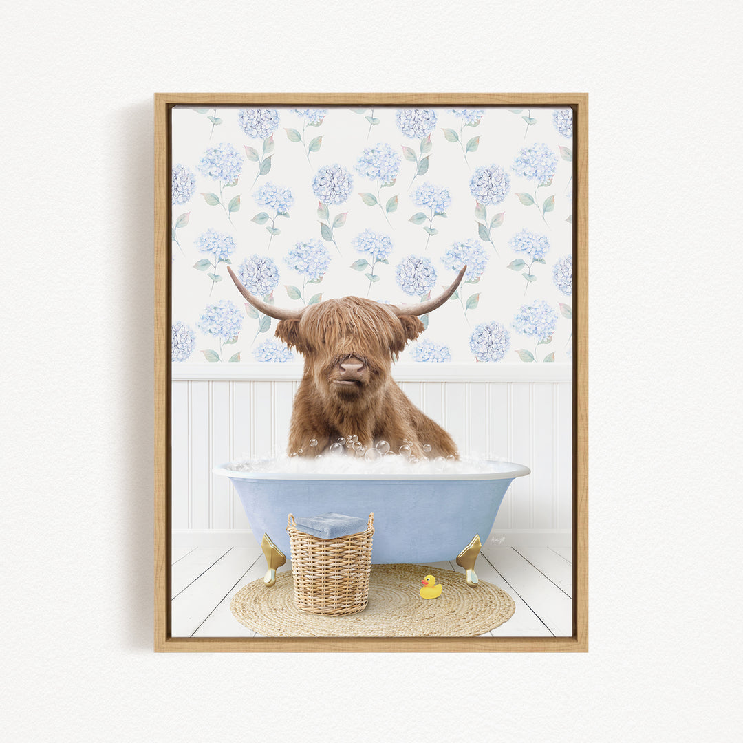 A brown cow with long horns is sitting in a blue bathtub filled with bubbles, surrounded by a wicker basket and rubber duckies.