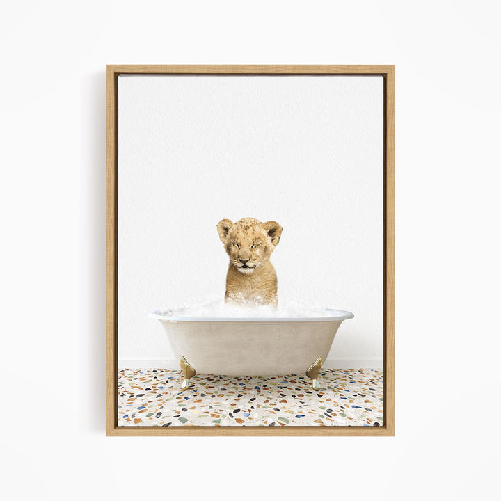 A young lion cub sitting in a white bathtub filled with water, looking directly at the camera.