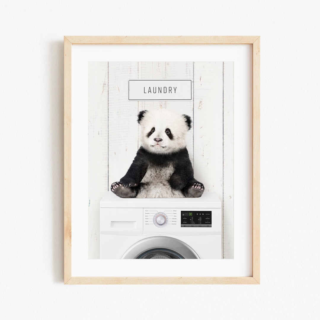 A panda bear sitting on top of a washing machine, with the word "Laundry" displayed above it.