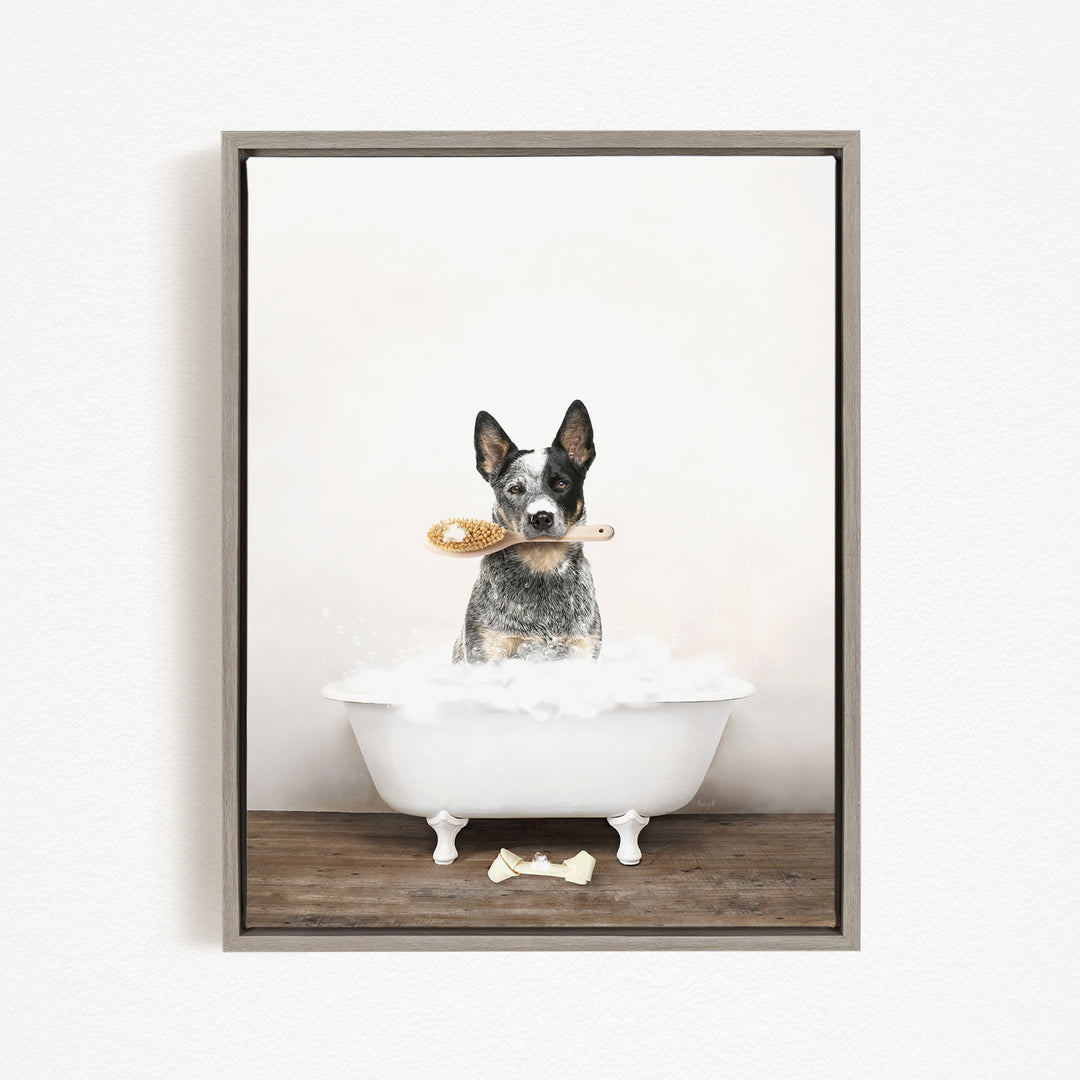A black and white dog sitting in a white bathtub, holding a yellow brush in its mouth.