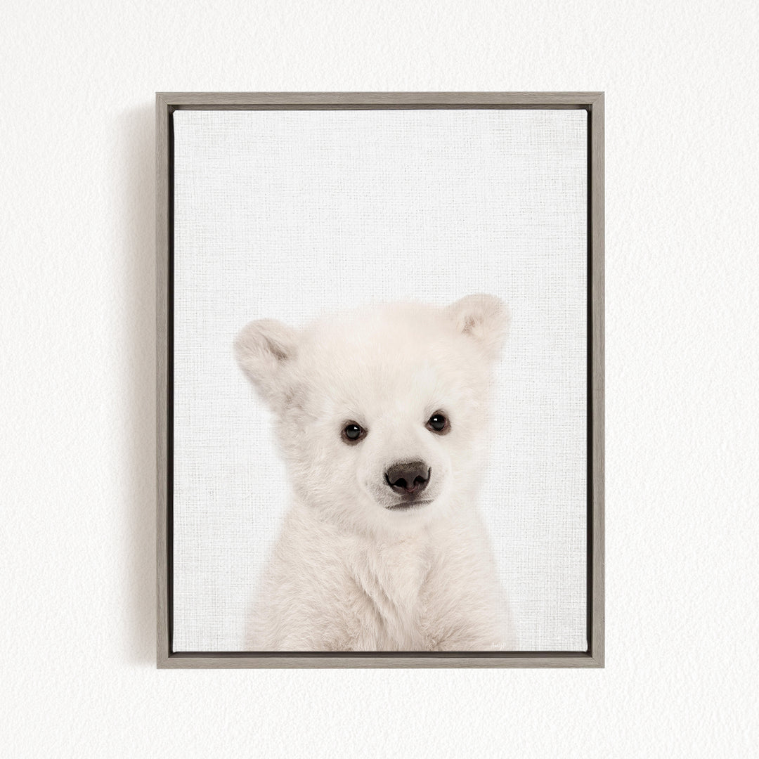 A cute white polar bear cub is the focus of the image, captured in a framed print against a plain white background.
