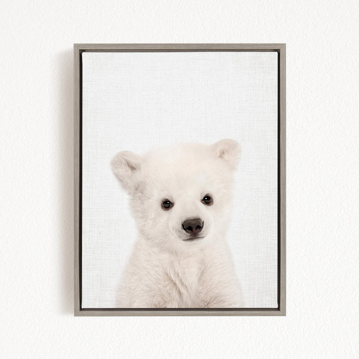 A cute white polar bear cub is the focus of the image, captured in a framed print against a plain white background.