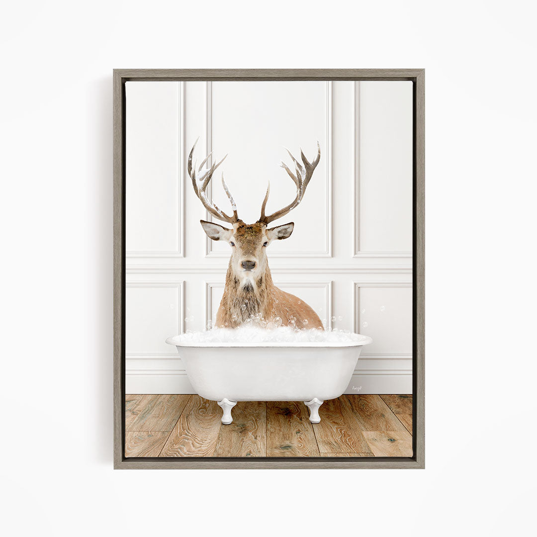 A deer with large antlers is sitting in a white bathtub filled with water, creating a whimsical and unexpected scene.