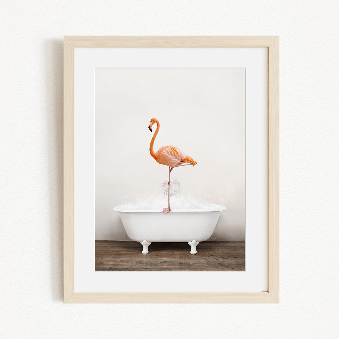 A framed image of a flamingo standing in a white bathtub filled with water.