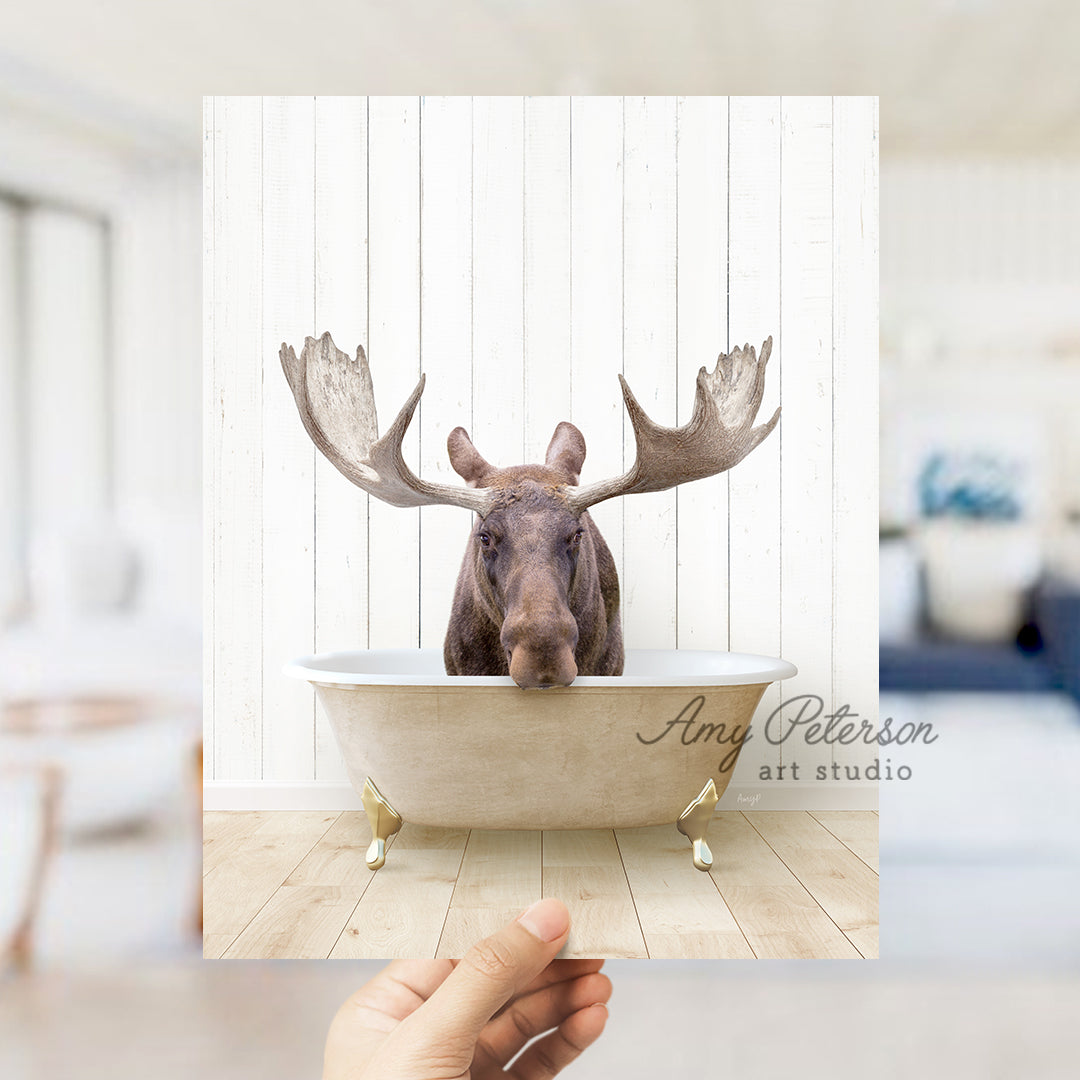 a hand holding a photo of a moose in a bathtub