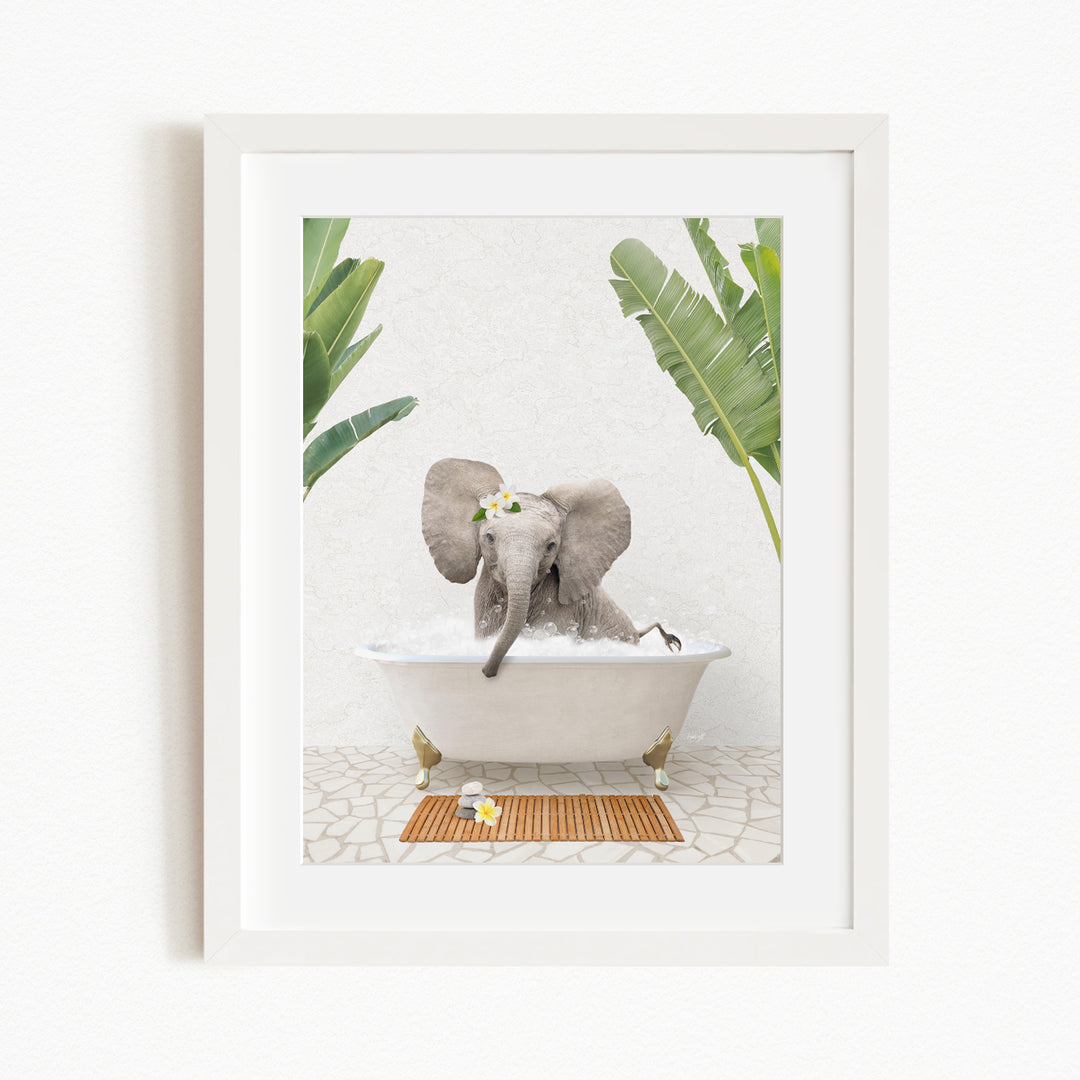 A baby elephant sitting in a bathtub filled with water, surrounded by green leaves and a wooden mat on the floor.