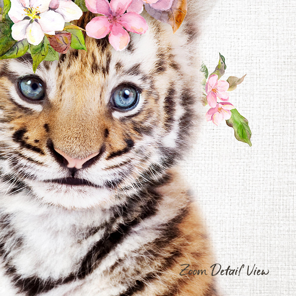 A close-up of a tiger cub's face, with its striking blue eyes and distinctive striped pattern, is the focal point of the image. The cub is adorned with a floral headpiece, adding a touch of whimsy to the scene. The background is a simple white canvas, which serves to highlight the details of the cub and its surroundings.