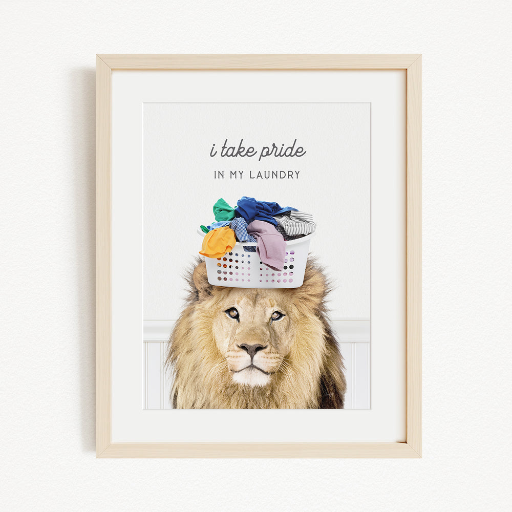 A framed image of a lion wearing a laundry basket on its head, with the text "I take pride in my laundry" above the image.