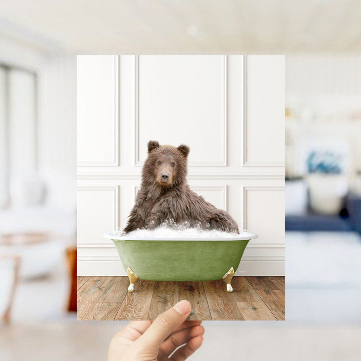 A brown bear sitting in a green bathtub filled with bubbles, with a blurred background suggesting a bathroom setting.