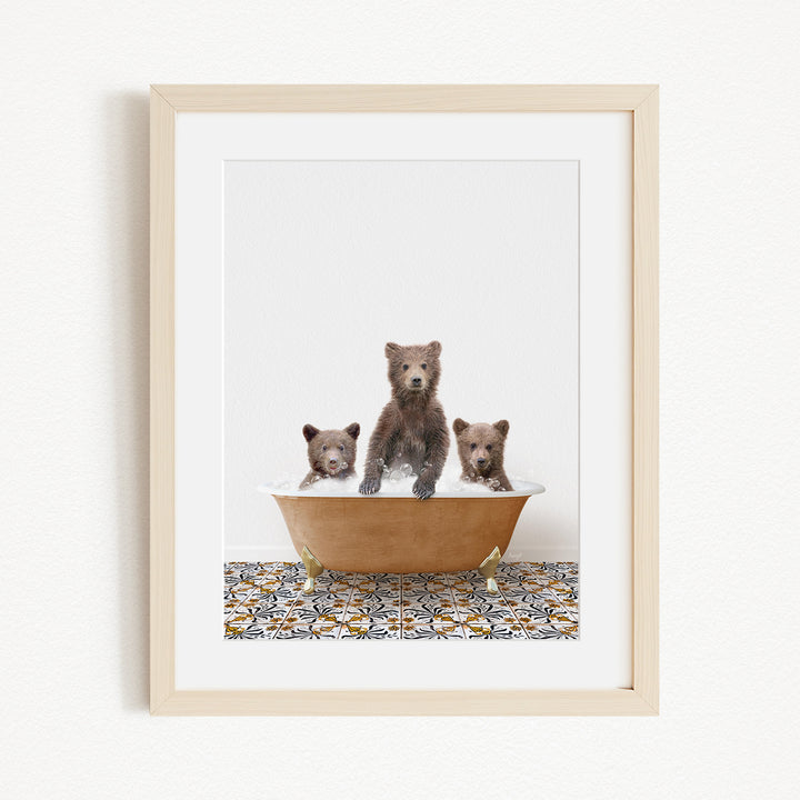 A framed image depicting three brown bears sitting in a bathtub filled with water, with a patterned tile floor beneath.