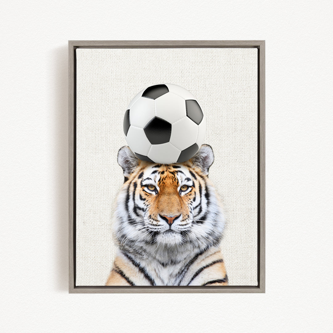 A tiger is sitting on a soccer ball, with the ball balanced on its head.