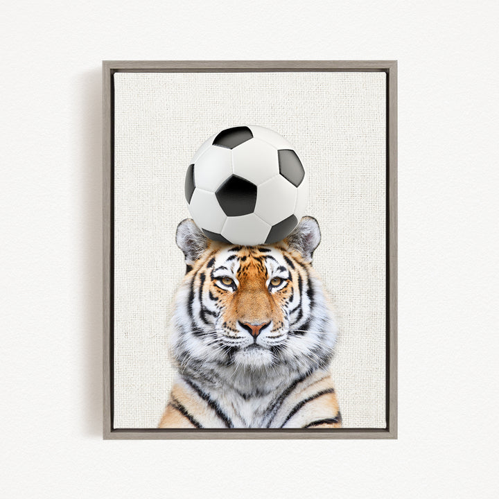 A tiger is sitting on a soccer ball, with the ball balanced on its head.