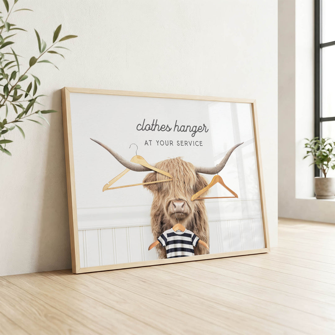 A framed poster with a bull's head and clothes hangers, accompanied by the text "clothes hanger at your service".