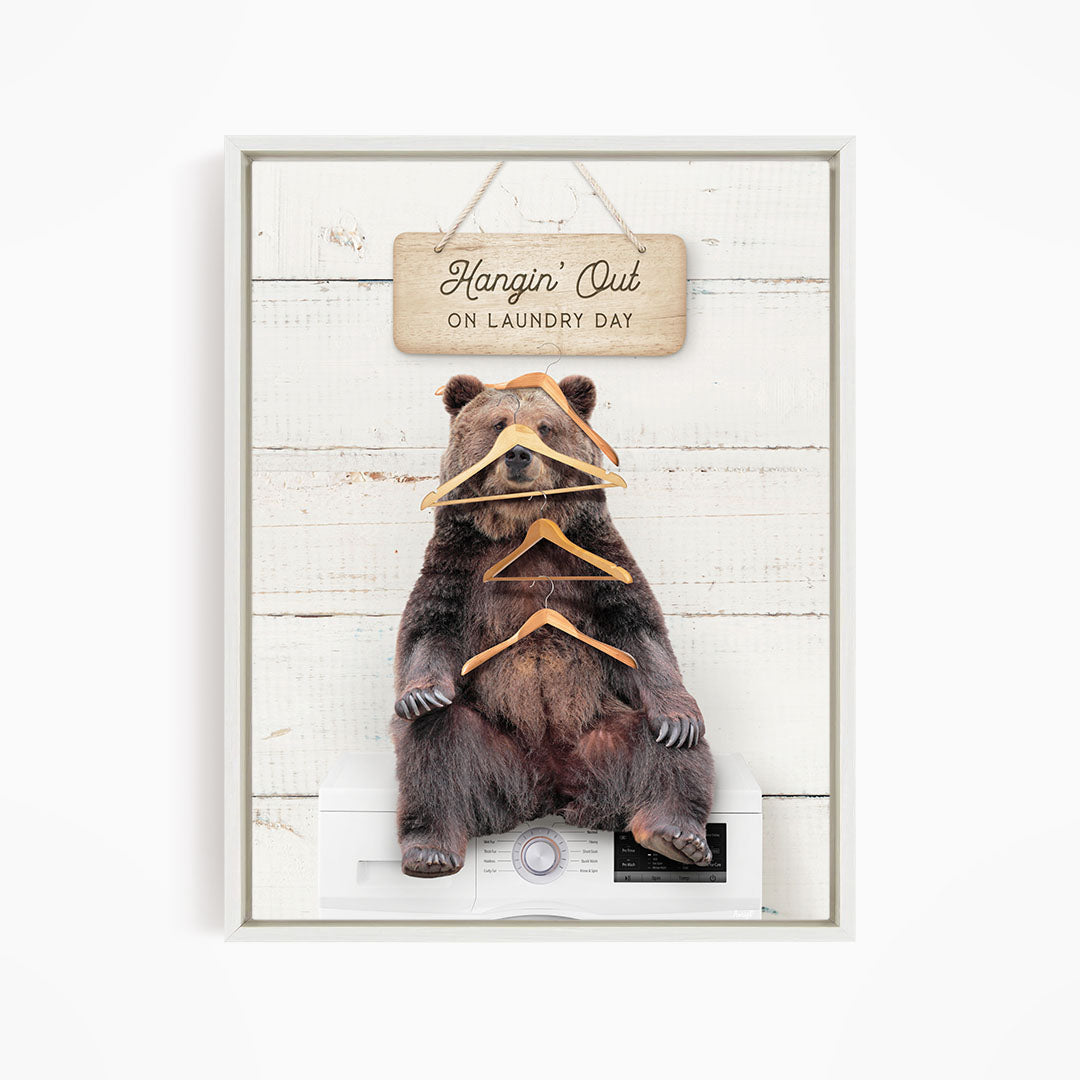 A framed image of a bear sitting on a washing machine, with a sign above it that says "Hangin' Out on laundry day".