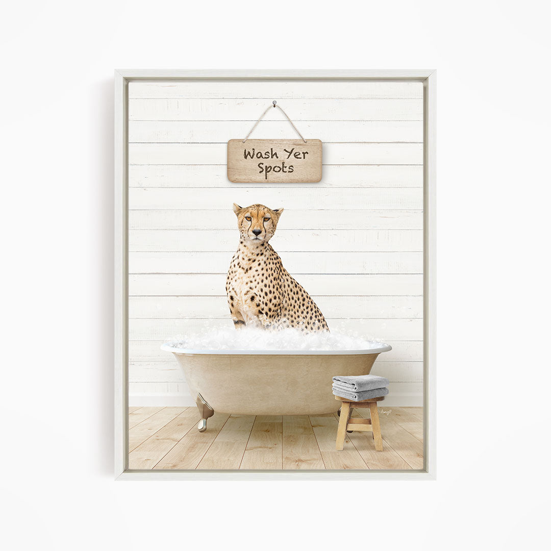 A cheetah sitting in a bathtub filled with water, with a sign above that reads "Wash Yer Spots".