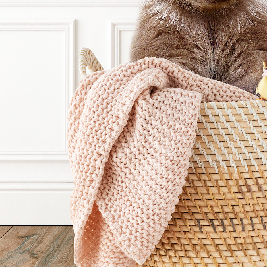 a cat is sitting in a basket with a blanket