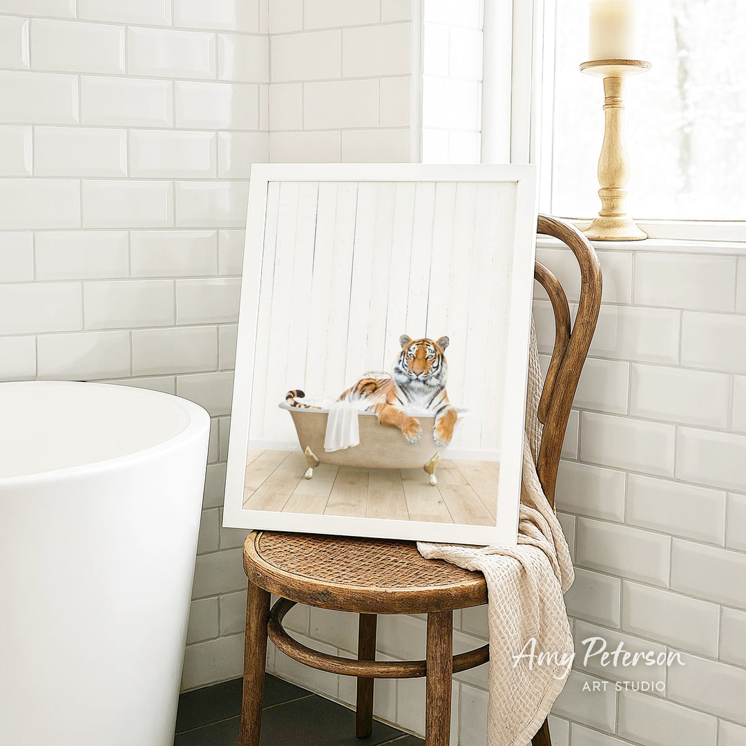 A framed image of a tiger sitting in a bathtub, with a towel draped over the side of the tub.