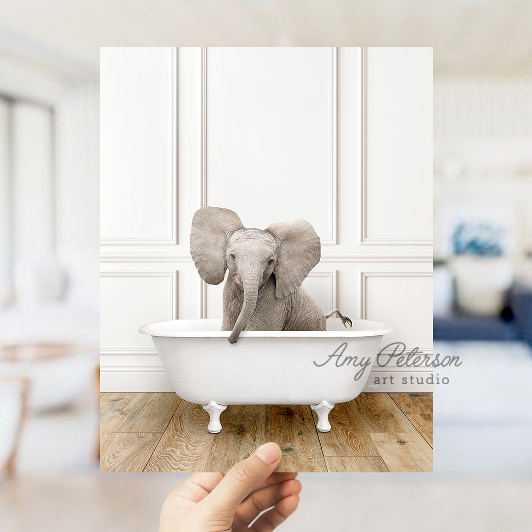 a hand holding a photo of an elephant in a bathtub