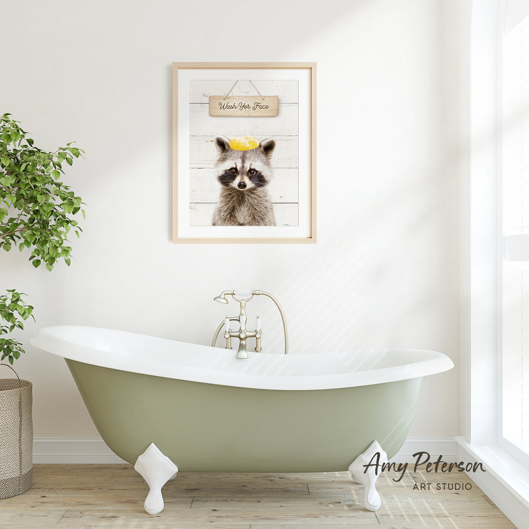 a green clawfoot bathtub with a framed picture of a raccoon above it, hanging on a white wall.